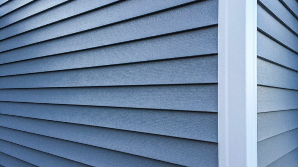Blue vinyl installed by a homeowner who learned about the benefits of stucco vs. vinyl siding